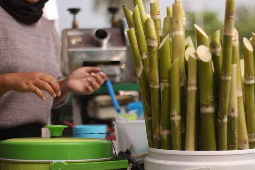 a woman in hijab working at a sugarcane juice street food stand